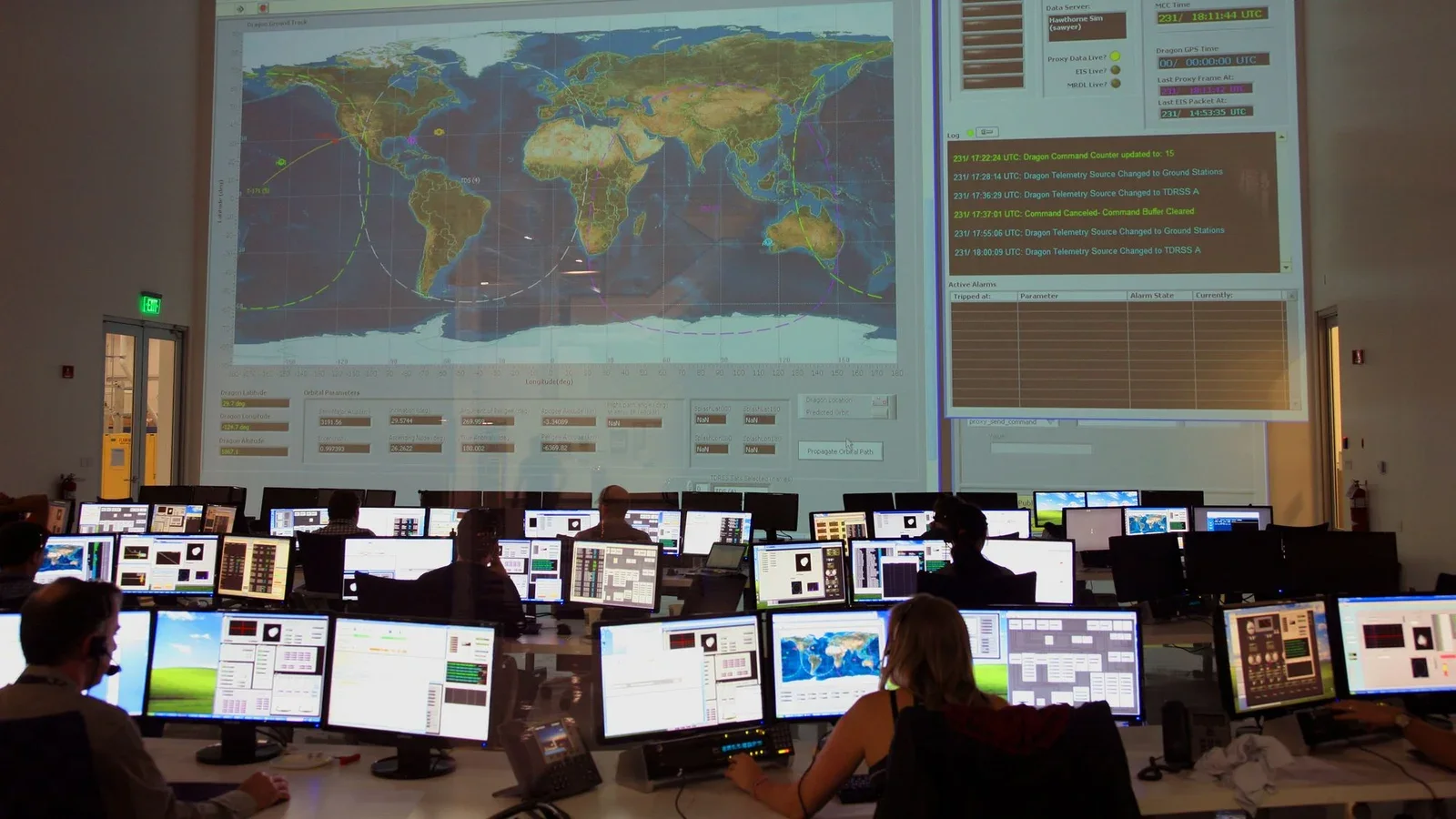 Control-room staff monitor global data across maps and computer screens.