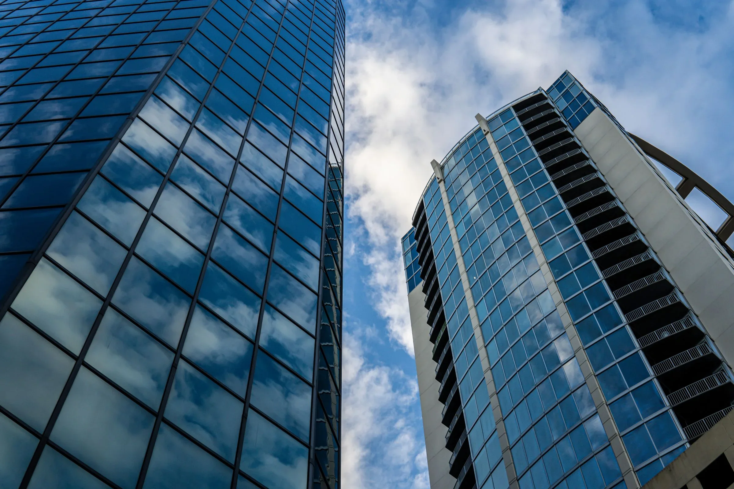 Low-angle view of glass office towers in a modern financial district.