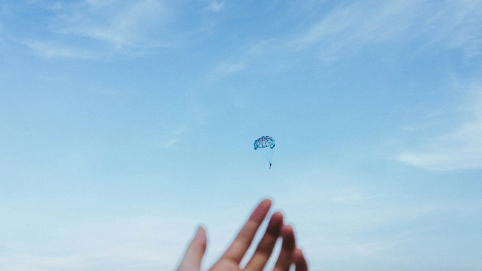 A person beneath a parachute; a visual metaphor for token airdrops