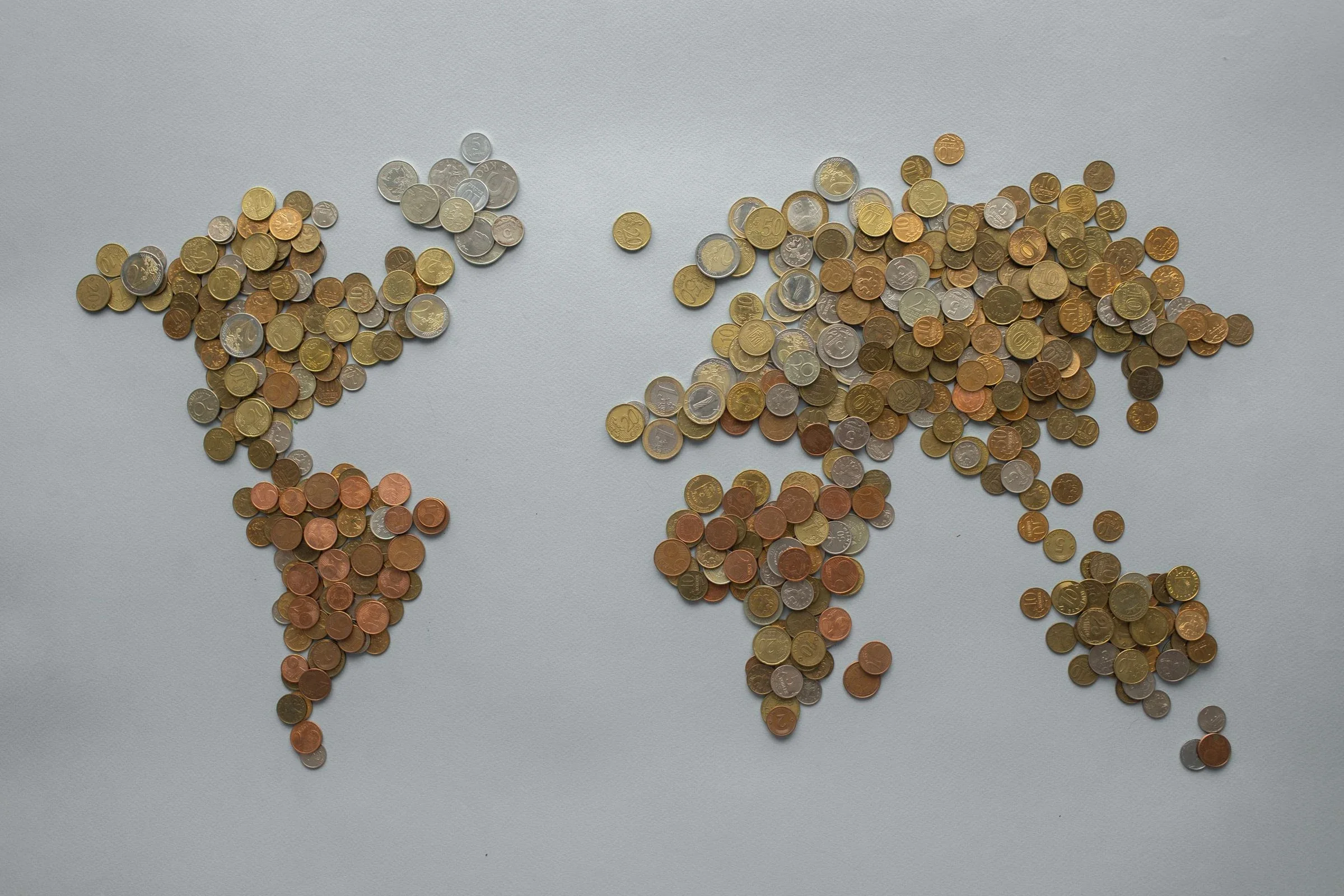 A world map assembled from international coins, representing global payments and finance.